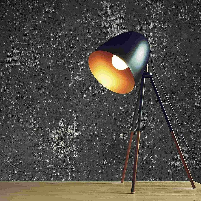 Tadessi Vliestapete M1-No.4075 - Schwarz, Sonstiges, 10,05 x 0,53 m - Dunkelblaue Tripod-Tischleuchte mit warm leuchtender Birne, auf Holztisch vor dunkler Texturwand.