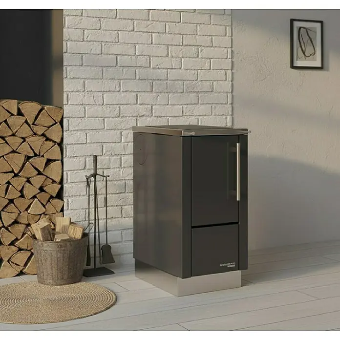 Haas+Sohn Küchenherd HS 40 - L x B x H: 600 x 400 x 852 cm, 5 kW, Schwarz - Ein moderner Kaminofen in Anthrazit mit Holzkorb und Kaminbesteck vor einer weißen Ziegelwand. Stimmungsvolles Ambiente für gemütliche Stunden.