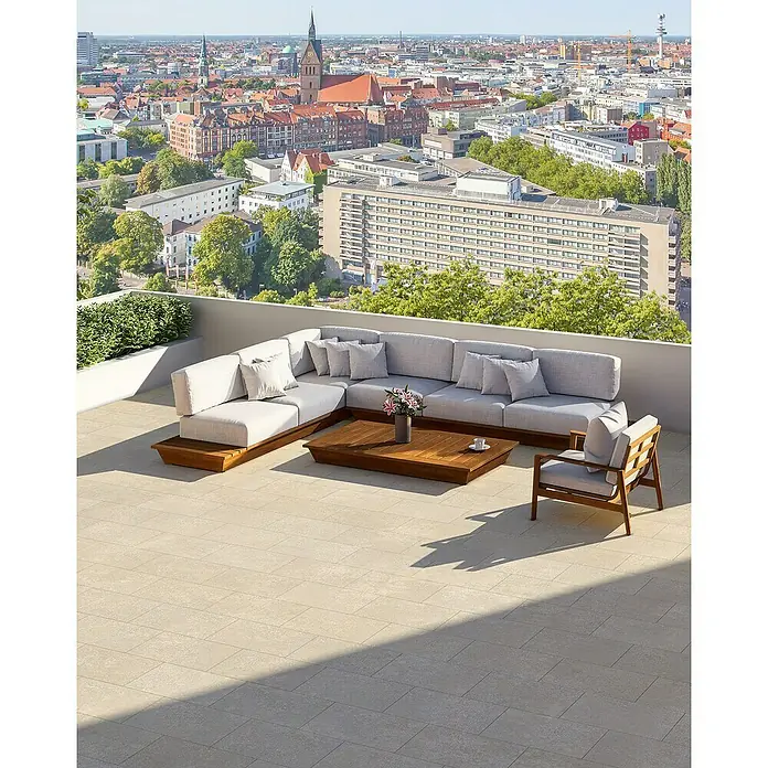 EHL Terrassenplatte Mantina - 60 x 40 x 4 cm, Greige, Beton - Moderne Lounge-Garnitur im Freien mit grauem Ecksofa, Holztisch und Sessel auf einer Dachterrasse mit Stadtblick.