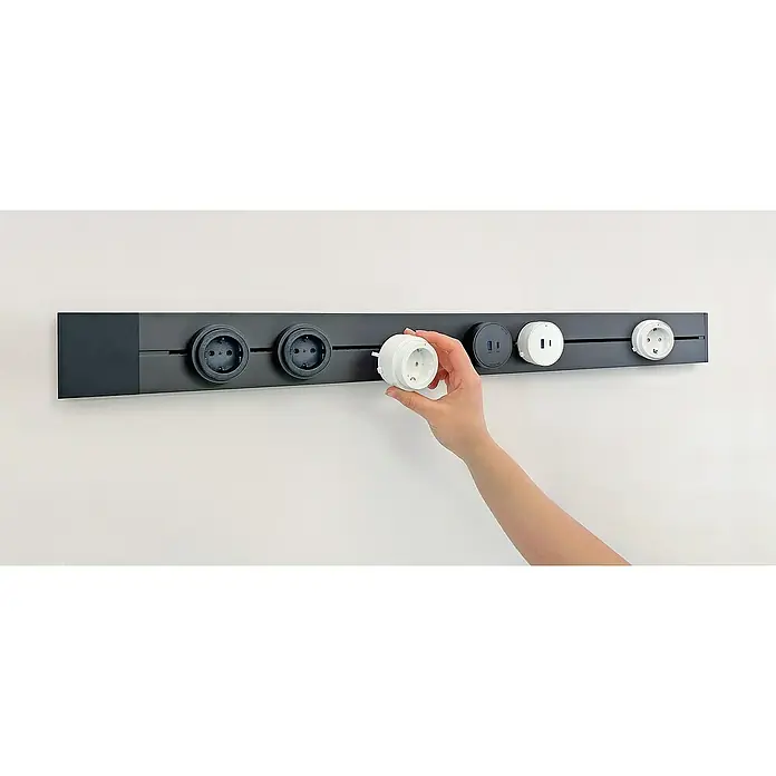 Schwaiger Steckdosenleiste Modulare Stromschiene - 100 cm, Schwarz, IP20, Ohne Schalter - Eine modulare Steckdosenleiste zur Wandmontage, mit austauschbaren Steckdosenaufsätzen und USB-Anschlüssen, wird von einer Hand bestückt.