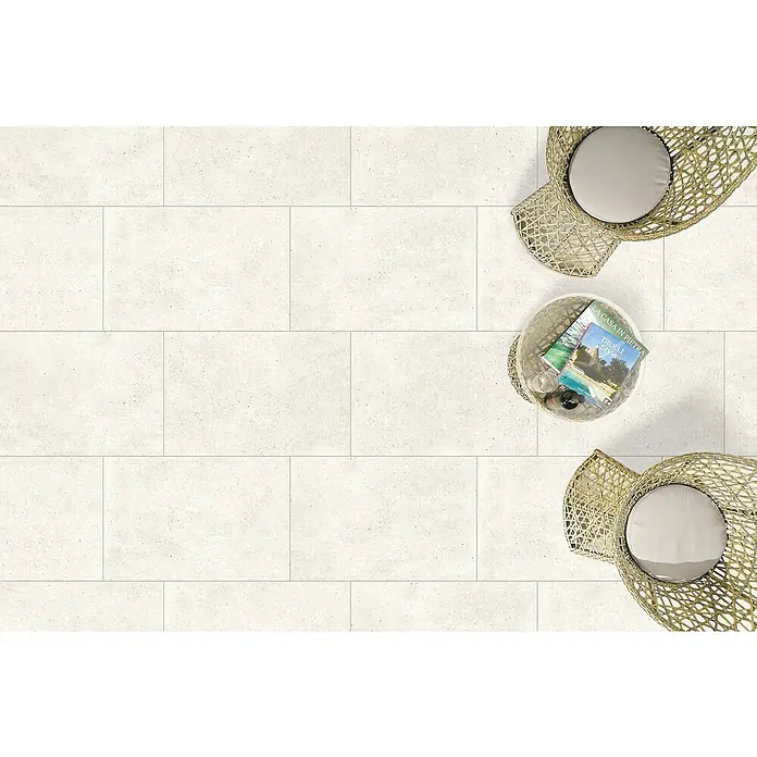 Terrassenfliese Duomo - 60 x 90 x 2 cm, Perla, Matt - Außenbereich mit hellen Steinzeugfliesen, ergänzt durch Korbmöbel und einem Beistelltisch mit Zeitschriften. Perfekt für entspannte Stunden im Freien.