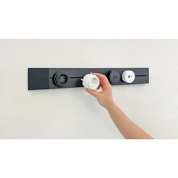 Schwaiger Steckdosenleiste Modulare Stromschiene - 50 cm, Schwarz, IP20, Ohne Schalter - Ein modulares Steckdosensystem in Schwarz mit einer Hand, die einen weißen Adapter einsetzt. Innovatives Design für flexible Stromversorgung.
