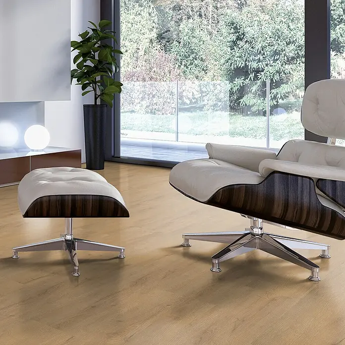 Vinylboden SPC - Eiche Solar, Landhausdiele, 1.220 x 182 x 4,3 mm - Sessel mit Hocker im Wohnzimmer. Der Sessel hat ein helles Leder und ein dunkles Holzgestell und ein poliertes Metallfußkreuz.