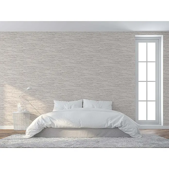 Tadessi Vliestapete M1-No.913 - Creme, Steinoptik, 10,05 x 0,53 m - Minimalistisches Schlafzimmer mit weißem Bett, grauem Rahmen und hellen Strukturwänden. Ein hohes Fenster lässt Licht herein.
