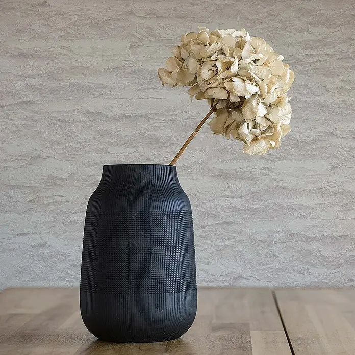 Tadessi Vliestapete M1-No.913 - Creme, Steinoptik, 10,05 x 0,53 m - Mattschwarze, texturierte Vase mit getrockneten, hellen Hortensienblüten auf einer Holzoberfläche.