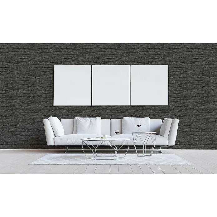 Tadessi Vliestapete M1-No.851 - Schwarz, Steinoptik, 10,05 x 0,53 m - Dunkelgraue strukturierte Wandverkleidung in einem modernen Wohnzimmer, hinter einem weißen Sofa und minimalistischer Kunst.