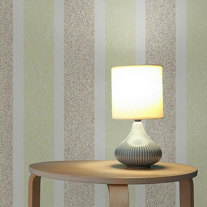 Tadessi Vliestapete M1-No.3839 - Braun, Streifen, 10,05 x 0,53 m - Beleuchtete gerippte graue Tischlampe mit weißem Schirm auf einem runden Holztisch.