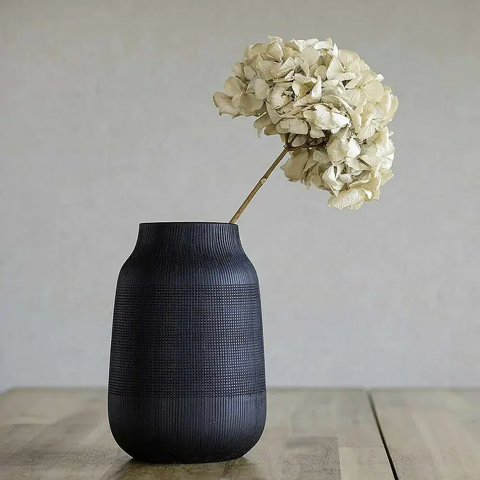 Tadessi Vliestapete M1-No.4407 - Grau, Sonstiges, 10,05 x 0,53 m - Schwarze strukturierte Vase mit getrockneter Hortensie auf einem Holztisch.