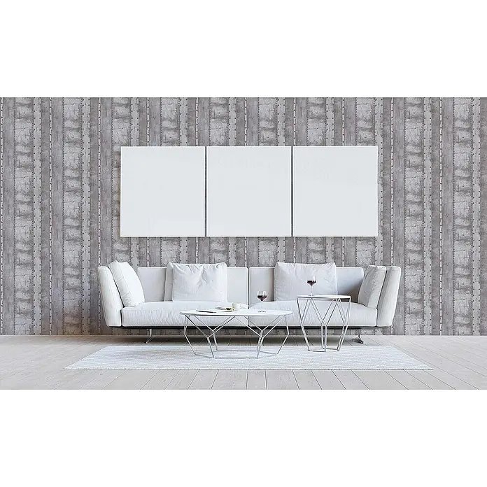 Tadessi Vliestapete M1-No.551 - Grau, Sonstiges, 10,05 x 0,53 m - Graue vertikal gestreifte Tapete mit Betonoptik im Industriedesign, schmückt ein modernes Wohnzimmer hinter einem weißen Sofa.
