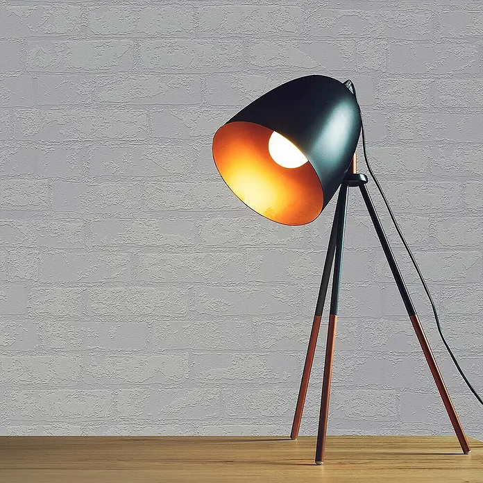 Tadessi Vliestapete M1-No.3233 - Weiß, Steinoptik, 10,05 x 0,53 m - Schwarze Schreibtischlampe mit goldener Innenseite und Stativfuß, auf Holztisch, spendet warmes Licht. Kupferakzente an den Beinen.