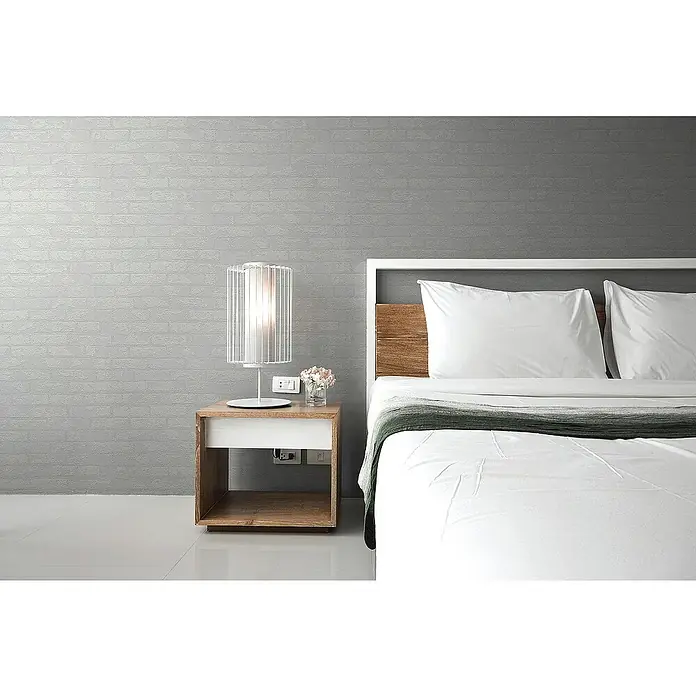 Tadessi Vliestapete M1-No.3233 - Weiß, Steinoptik, 10,05 x 0,53 m - Modernes Schlafzimmer: Bett mit weißer Bettwäsche, Holzkopfteil und grauem Überwurf. Daneben ein Nachttisch mit Lampe.