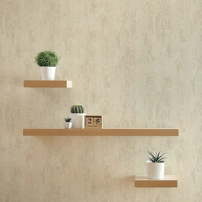 Tadessi Vliestapete M1-No.63 - Creme, Steinoptik, 10,05 x 0,53 m - Drei schwebende Regale aus hellem Holz präsentieren Topfpflanzen und Deko an einer strukturierten Wand.