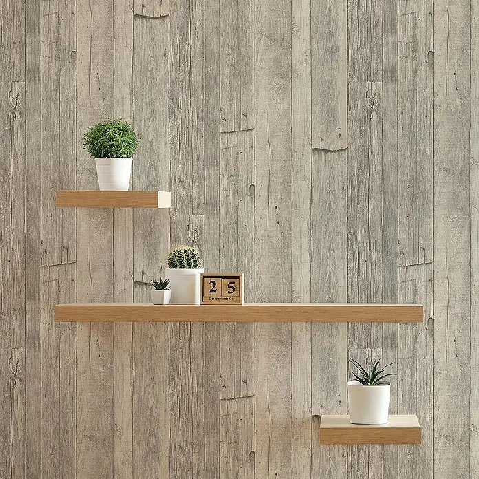 Tadessi Vliestapete M1-No.916 - Grau, Holzoptik, 10,05 x 0,53 m - Drei helle Holz-Schweberegale mit Topfpflanzen und einem Kalender an einer strukturierten Wand.