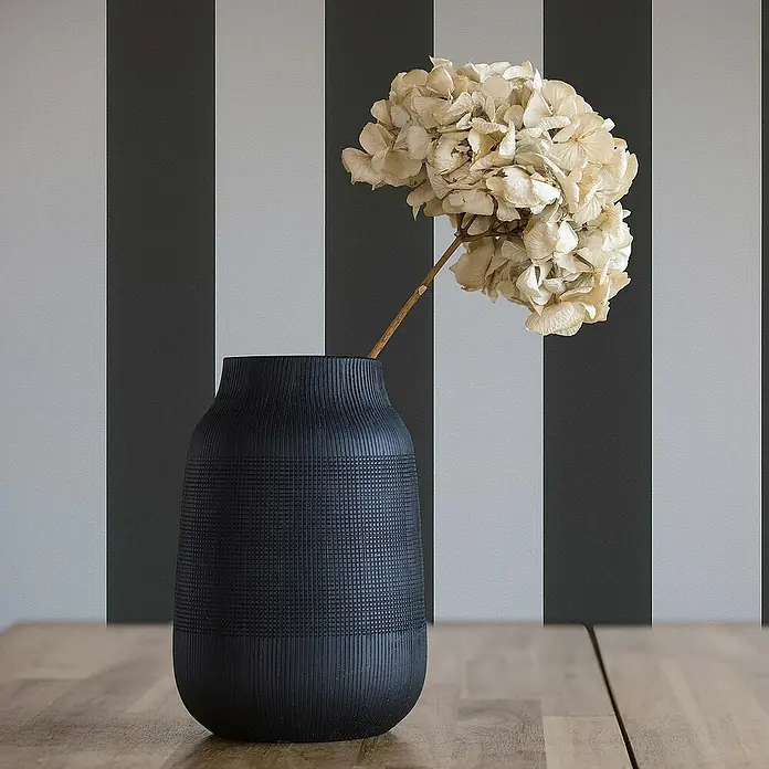 Tadessi Vliestapete M1-No.74 - Schwarz, Streifen, 10,05 x 0,53 m - Dunkle, texturierte Vase mit Trockenblumen auf einer Holzoberfläche stehend.