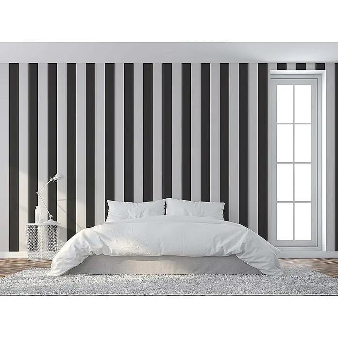Tadessi Vliestapete M1-No.74 - Schwarz, Streifen, 10,05 x 0,53 m - Schlafzimmer mit schwarz-weiß gestreifter Tapete und einem weißen Bett mit passender Bettwäsche.