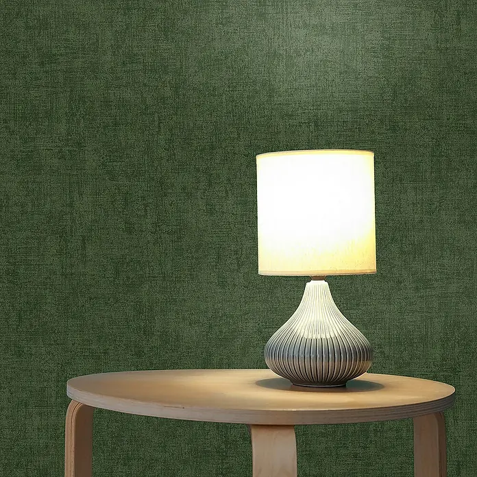 Tadessi Vliestapete M1-No.1051 - Grün, Uni, 10,05 x 0,53 m - Beleuchtete Tischlampe mit hellem Schirm und geripptem birnenförmigem Fuß auf einem runden Holztisch.