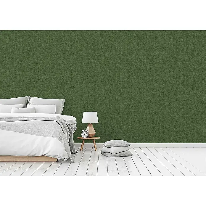 Tadessi Vliestapete M1-No.1051 - Grün, Uni, 10,05 x 0,53 m - Strukturierte, dunkelgrüne Tapete in einem modernen Schlafzimmer, die eine beruhigende Kulisse hinter einem Bett mit weißer Bettwäsche bildet.