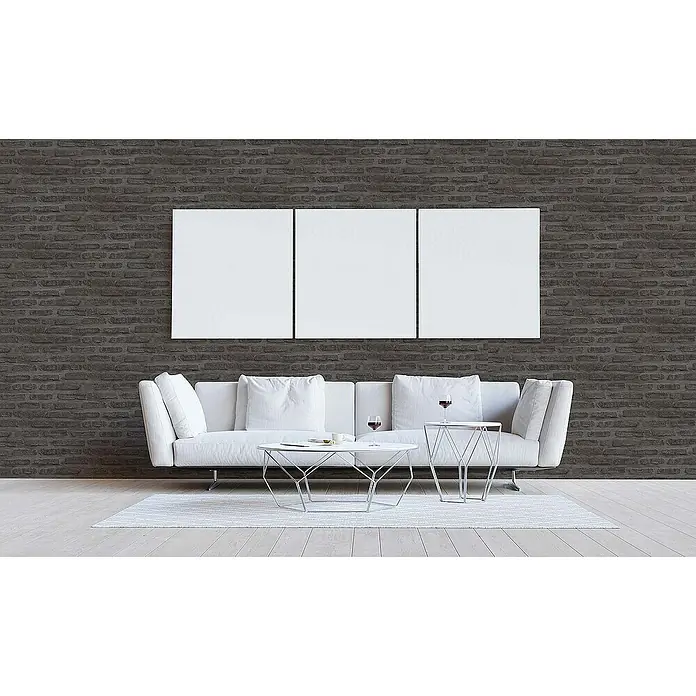 Tadessi Vliestapete M1-No.419 - Schwarz, Steinoptik, 10,05 x 0,53 m - Drei große, leere weiße Leinwände nebeneinander an einer dunklen Ziegelwand über einem weißen Sofa, bereit für individuelle Kunst.