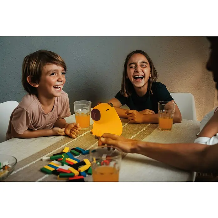 FHL easy LED-Nachtlicht Piggy - 0,5 W, L x B x H: 11 x 10 x 12 cm, RGBW, Capybara Piggy - Kinder lachen am Tisch mit Getränken und einem Capybara-Nachtlicht, das eine warme, beruhigende Atmosphäre schafft.