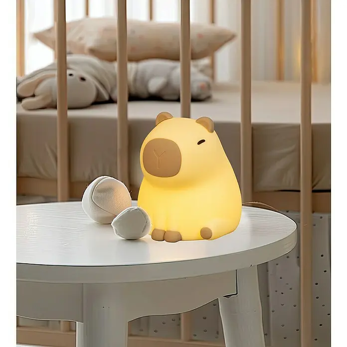 FHL easy LED-Nachtlicht Piggy - 0,5 W, L x B x H: 11 x 10 x 12 cm, RGBW, Capybara Piggy - Das Nachtlicht in Form eines Capybara-Baby ist ein süßes, gelbes und ideales Geschenk für Kinder. Es steht auf einem Beistelltisch mit kleinen Spielbällen.