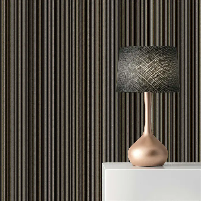 Tadessi Vliestapete M1-No.880 - Schwarz, Streifen, 10,05 x 0,7 m - Roségoldene Tischlampe mit dunklem, gemustertem Schirm auf weißer Fläche vor einer gestreiften Wand.