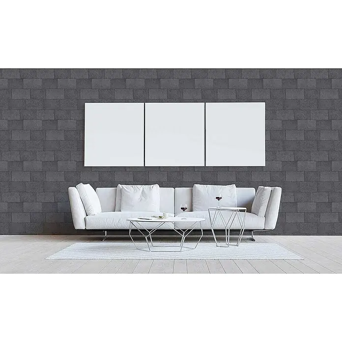 Tadessi Vliestapete M1-No.3395 - Grau, Steinoptik, 10,05 x 0,53 m - Drei leere, weiße rechteckige Leinwände zusammen an einer dunklen Wand über einem Sofa, bereit für Kunst.