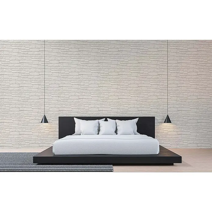 Tadessi Vliestapete M1-No.847 - Grau, Steinoptik, 10,05 x 0,53 m - Modernes Bett mit schwarzem Plattformgestell, weißer Bettwäsche und drei Kissen, flankiert von zwei schwarzen Pendelleuchten vor einer hellen Strukturwand.