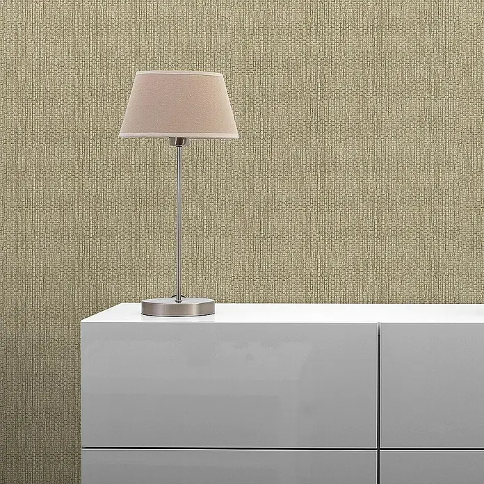 Tadessi Vliestapete M1-No.1730 - Grau, Sonstiges, 10,05 x 0,53 m - Tischlampe mit beigem Stoffschirm und gebürstetem Metallsockel auf einem weißen Schrank vor einer strukturierten beigefarbenen Wand.