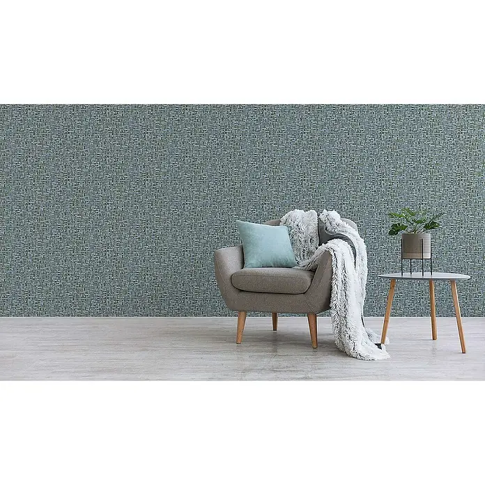 Tadessi Vliestapete M1-No.1534 - Blau, Holzoptik, 10,05 x 0,53 m - Texturierte blau-graue und grüne Tapete in Weboptik schmückt eine Wand in einem modernen Wohnraum mit Sessel.