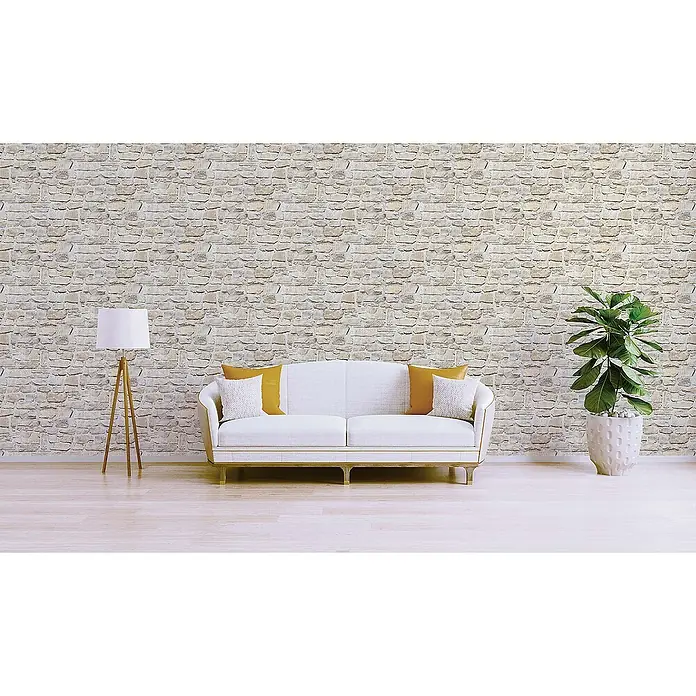 Tadessi Vliestapete M1-No.9 - Grau, Steinoptik, 10,05 x 0,53 m - Hell getönte Wand mit Steinmuster als Hintergrund in einem modernen Wohnzimmer mit Sofa, Lampe und Pflanze.