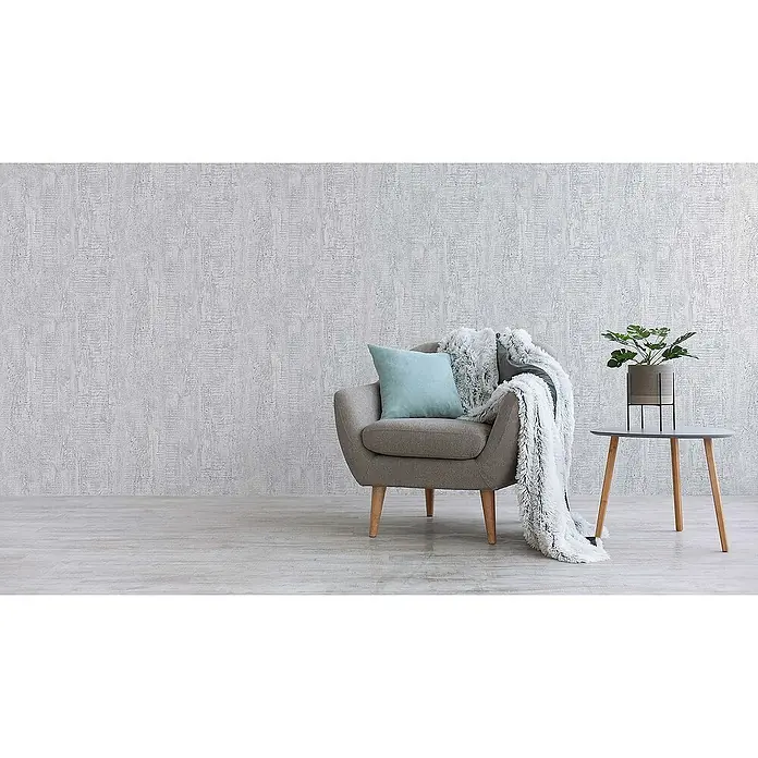Tadessi Vliestapete M1-No.893 - Weiß, Steinoptik, 10,05 x 0,53 m - Gemütliche Einrichtung mit grauem Sessel, blauem Kissen, flauschiger Decke und Beistelltisch mit Pflanze.