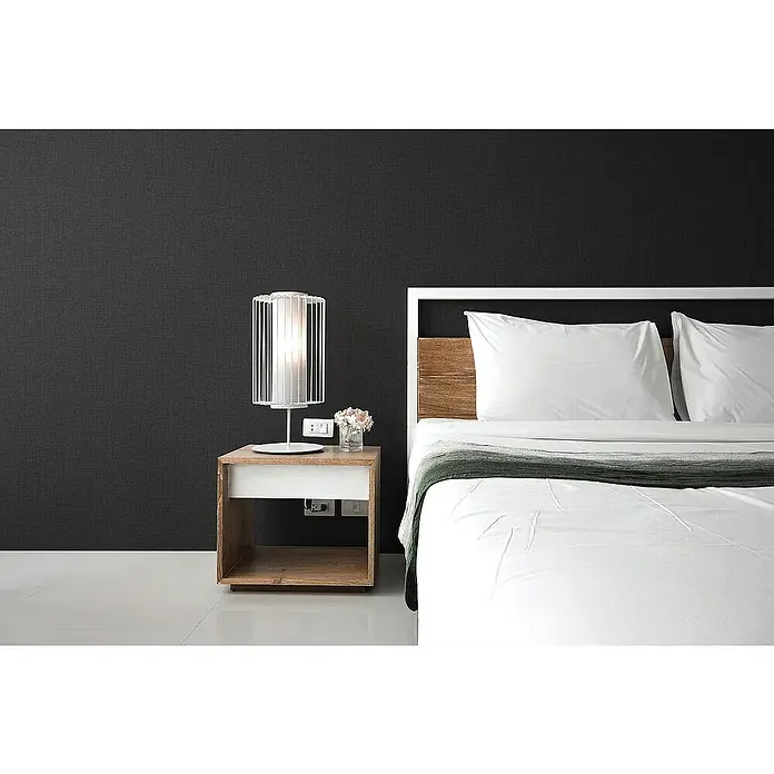 Tadessi Vliestapete M1-No.1257 - Schwarz, Uni, 10,05 x 0,53 m - Modernes Schlafzimmer mit weißem Bett, Holzkopfteil, dunkelgrauer Wand und Nachttisch mit Lampe.