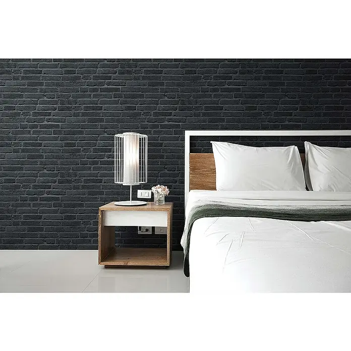 Tadessi Vliestapete M1-No.890 - Schwarz, Steinoptik, 10,05 x 0,53 m - Schwarze Ziegelwand in einem modernen Schlafzimmer mit weißem Bett und Holznachttisch.