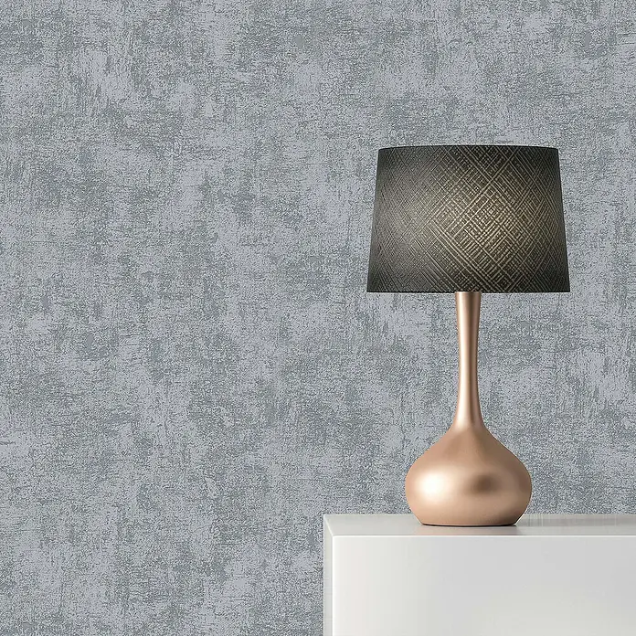 Tadessi Vliestapete M1-No.15 - Grau, Steinoptik, 10,05 x 0,53 m - Roségoldene Tischlampe mit dunklem, gemustertem Lampenschirm auf weißer Fläche.