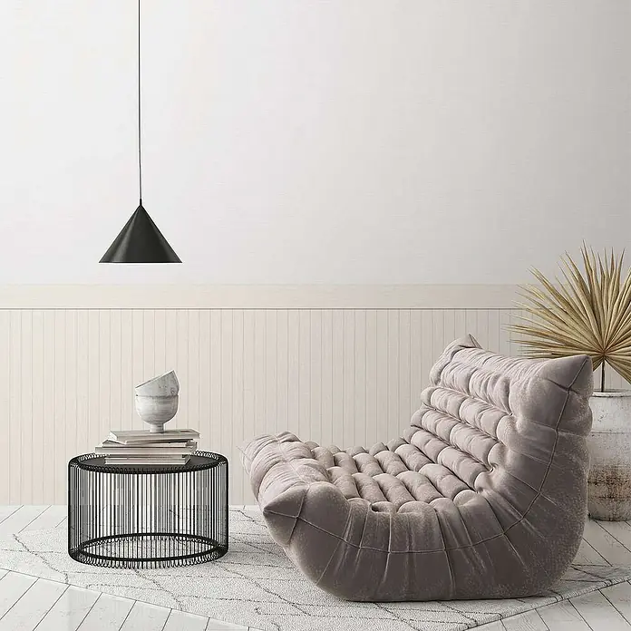 Tadessi Vliestapete 0 - Grau, Streifen, 5 x 1,06 m - Eine plüschige, getuftete helltaupefarbene Chaiselongue in einem minimalistischen Wohnzimmer, neben einem schwarzen Draht-Beistelltisch und einer Pendelleuchte.