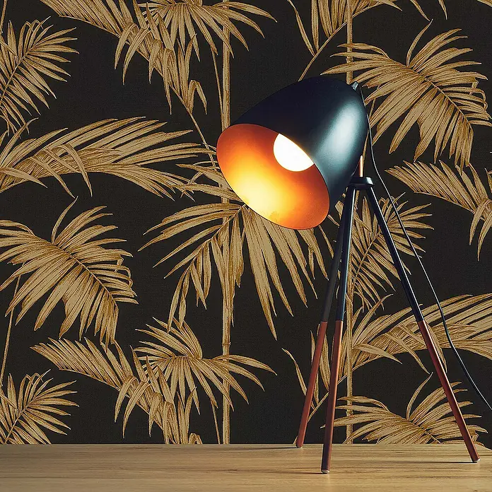 Tadessi Vliestapete M1-No.274 - Schwarz, Floral, 10,05 x 0,53 m - Schwarze Stativ-Stehleuchte mit glühender Birne, auf Holzfußboden vor dunkler Palmenblatt-Tapete.