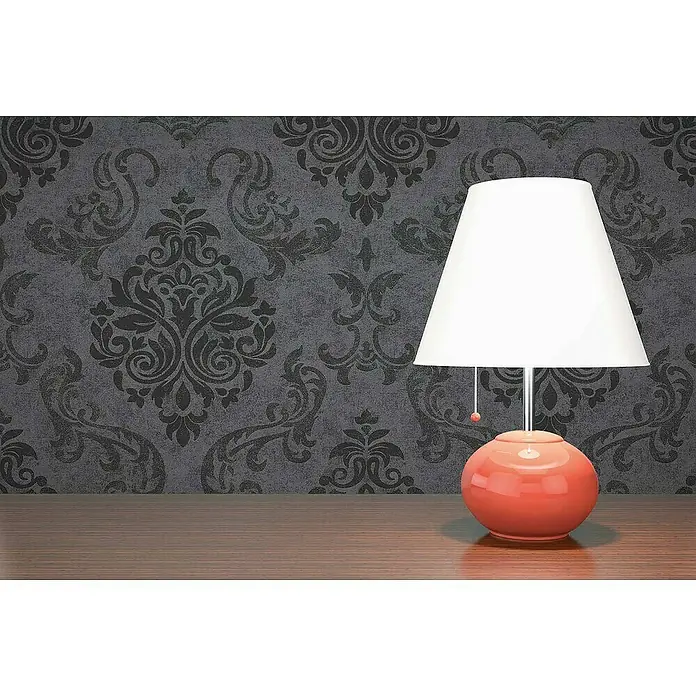 Tadessi Vliestapete M1-No.901 - Schwarz, Ornament, 10,05 x 0,53 m - Korallenfarbene Tischlampe mit weißem Schirm auf Holztisch vor gemusterter Wand.