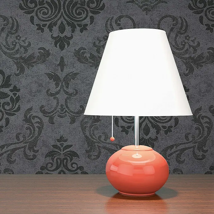 Tadessi Vliestapete M1-No.901 - Schwarz, Ornament, 10,05 x 0,53 m - Tischlampe mit weißem Schirm und glänzend korallenrotem Fuß auf Holztisch vor dunkler Damasttapete.