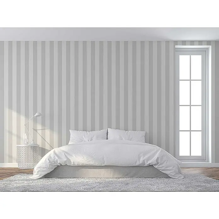 Tadessi Vliestapete M1-No.2243 - Grau, Streifen, 10,05 x 0,53 m - Minimalistisches Schlafzimmer mit Bett, weißer Bettwäsche, grauem Bettgestell und flauschigem Teppich. Gestreifte Wände und ein hohes Fenster.