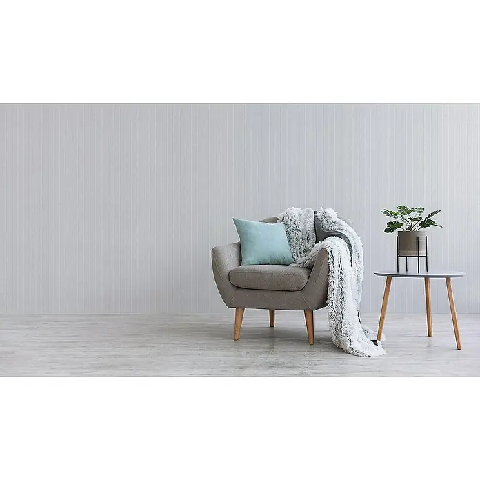 Tadessi Vliestapete M1-No.3621 - Weiß, Streifen, 10,05 x 0,53 m - Grauer Sessel mit blauem Kissen und weißem Überwurf, daneben ein runder Beistelltisch mit Grünpflanze.