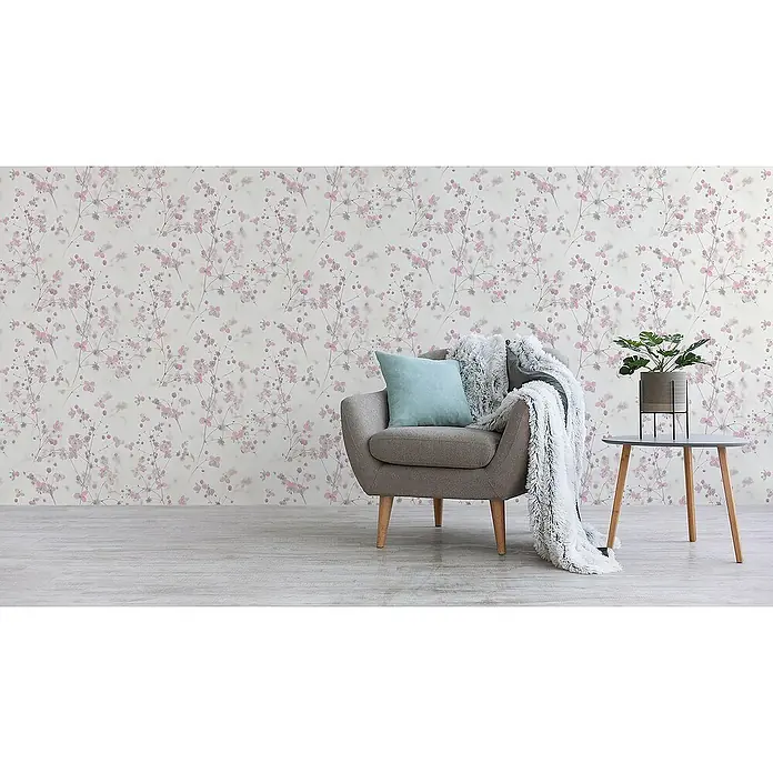 Tadessi Vliestapete M1-No.3574 - Rosa, Floral, 10,05 x 0,53 m - Zarte rosa-graue Blumentapete schafft eine ruhige Kulisse in einem Raum mit gemütlichem Sessel und Beistelltisch.