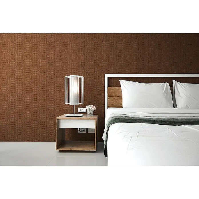 Tadessi Vliestapete M1-No.1733 - Schwarz, Sonstiges, 10,05 x 0,53 m - Braune strukturierte Wandverkleidung hinter einem Bett mit weißer Bettwäsche und einem Nachttisch mit Lampe.