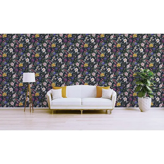 Tadessi Vliestapete M1-No.348 - Blau, Floral, 10,05 x 0,53 m - Blumentapete mit dunklem Hintergrund und bunten Blüten in Pink, Gelb, Blau und Weiß an einer Wohnzimmerwand hinter einem weißen Sofa.