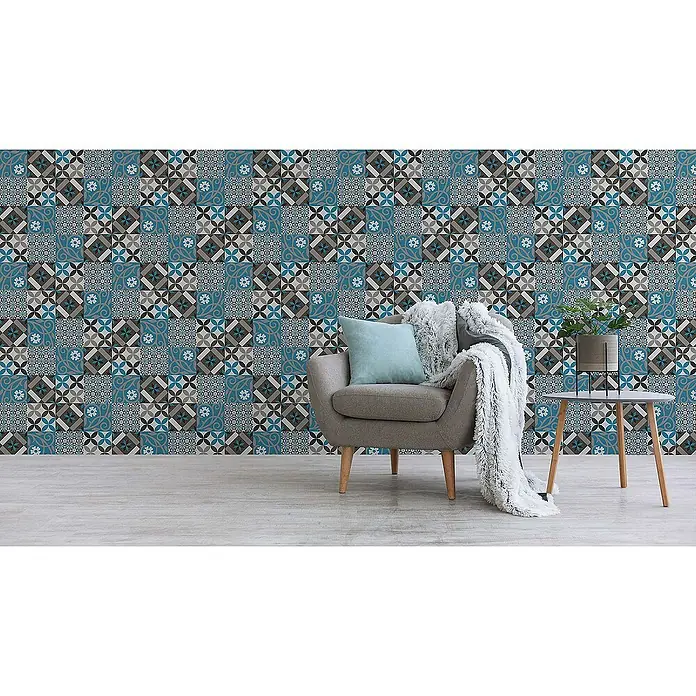 Tadessi Vliestapete M1-No.522 - Schwarz, Fliesenoptik, 10,05 x 0,53 m - Blau, grau und schwarz gemusterte Tapete mit Mosaikdesign, die eine Wand in einem gemütlichen Raum mit Sessel und Pflanze schmückt.