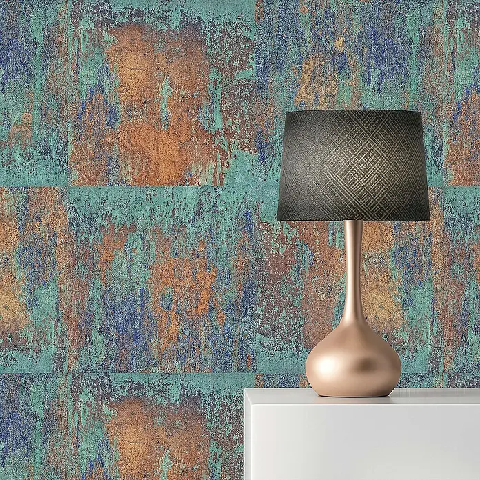 Tadessi Vliestapete M1-No.152 - Blau, Sonstiges, 10,05 x 0,53 m - Eine roségoldene Tischlampe mit dunklem, texturiertem Schirm steht auf einer weißen Fläche vor einer verwitterten, farbigen Wand.