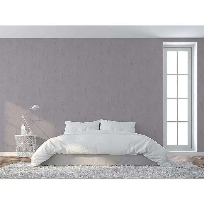 Tadessi Vliestapete M1-No.1611 - Grau, Steinoptik, 10,05 x 0,53 m - Ein minimalistisches Schlafzimmer mit einem großen Bett mit weißer Bettwäsche und hellgrauem Bettrock vor einer strukturierten violetten Wand.