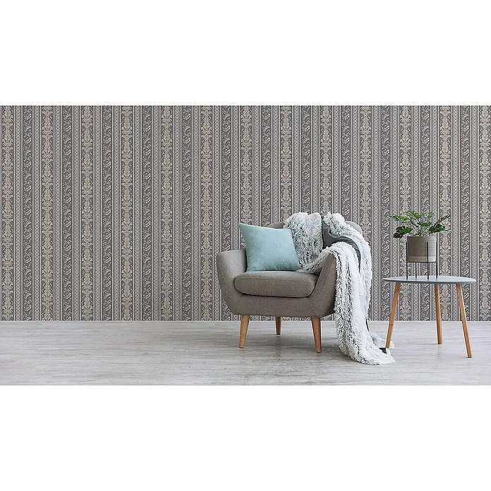 Tadessi Vliestapete M1-No.2427 - Grau, Streifen, 10,05 x 0,53 m - Elegante gestreifte Tapete mit floralen Mustern in Anthrazit und Beige an einer Zimmerwand hinter einem Sessel.