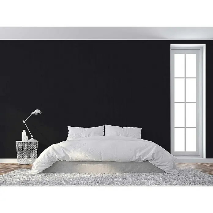 Tadessi Vliestapete M1-No.3895 - Schwarz, Uni, 10,05 x 0,53 m - Minimalistisches Schlafzimmer mit einem weiß bezogenen Bett, einem weißen Metallbeistelltisch und einer verstellbaren weißen Lampe.