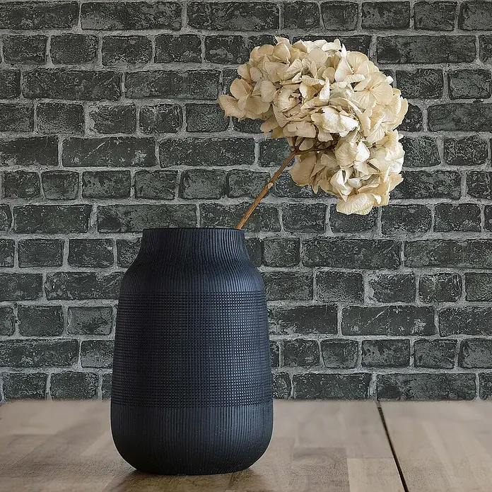 Tadessi Vliestapete M1-No.45 - Schwarz, Steinoptik, 10,05 x 0,53 m - Mattschwarze Vase mit Rippen- und Gittertexturen, hält Trockenblumen auf Holzfläche.