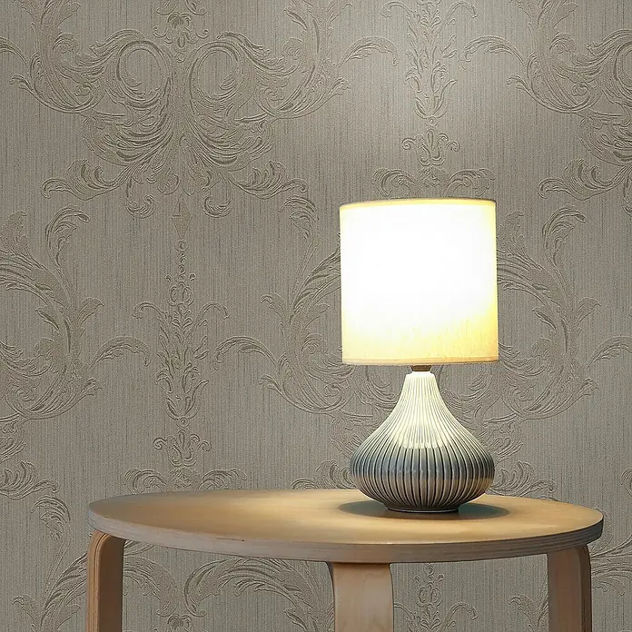 Tadessi Vliestapete M1-No.3860 - Braun, Streifen, 10,05 x 0,53 m - Tischlampe mit geripptem blau-grauem Keramikfuß und leuchtendem Stoffschirm auf einem runden Holztisch.